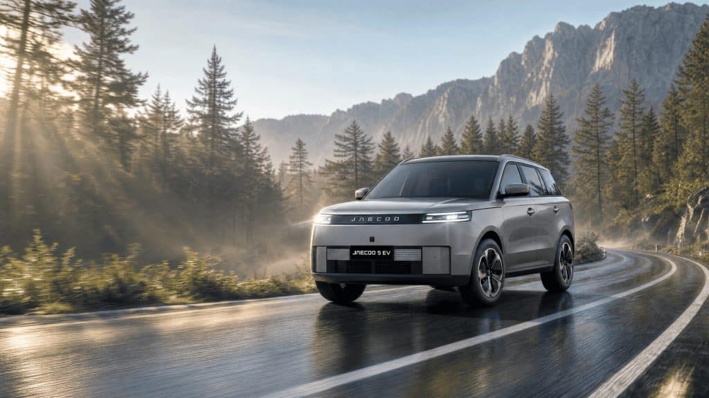 Jaecoo 5 100 % électrique gris roulant sur une route de montagne au lever du soleil