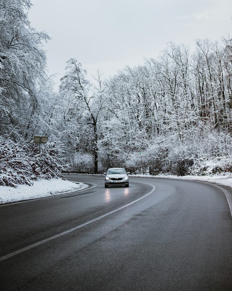 Voiture roulant sur une route de forêt enneigée, phares allumés